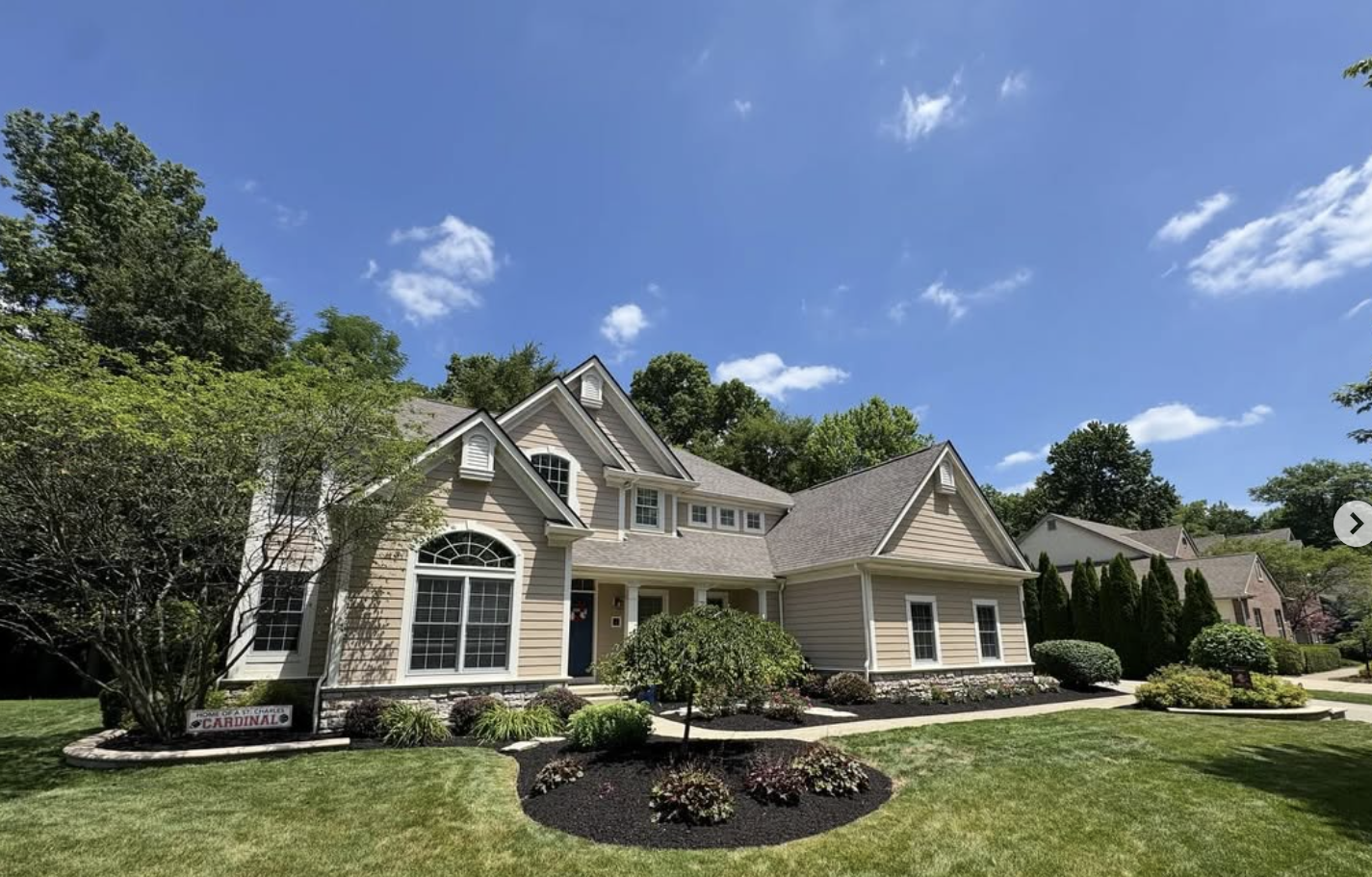Cape-style home with mature landscaping, manicured beds, and clean lawn edges